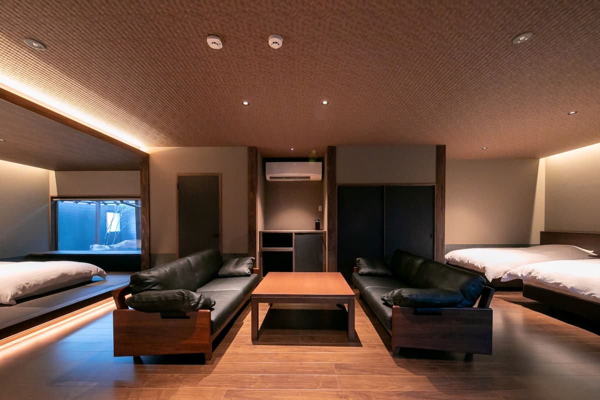 Quarto de hotel moderno com duas camas, um sofá, uma mesa de centro e uma televisão.