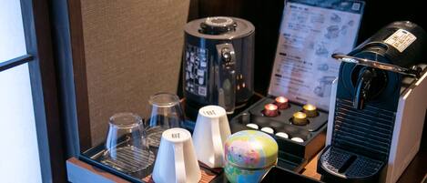 Un minibar con cafetera, tetera, vasos y un pequeño globo terráqueo.