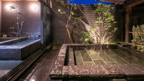 A spa area with a stone wall, a wooden ceiling, and a small tree. - yumotoankiyohime (Kirishima)