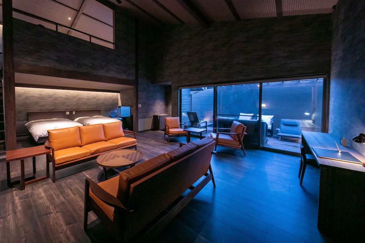 Quarto de hotel moderno com uma cama grande, sofá, escrivaninha e varanda com vista.