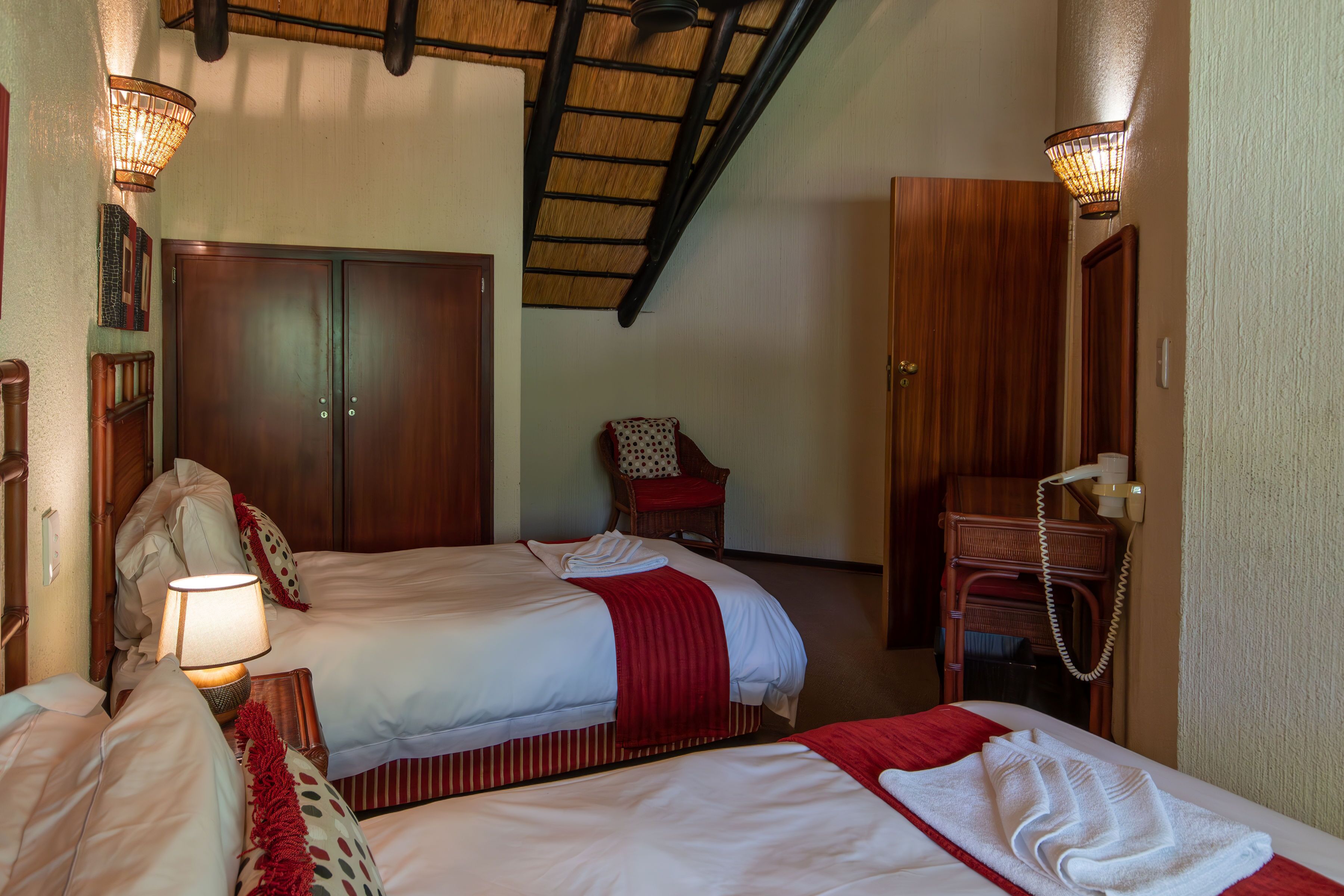 Habitación de hotel con dos camas, un armario de madera, una silla y un escritorio con teléfono.