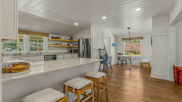 Una cocina moderna con una isla grande, taburetes de bar de madera y una zona de comedor con mesa y sillas.