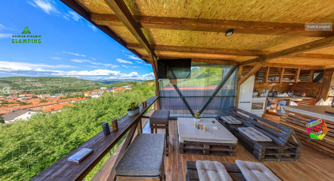 Un área de glamping con mobiliario de madera, cocina y vistas a un pueblo.