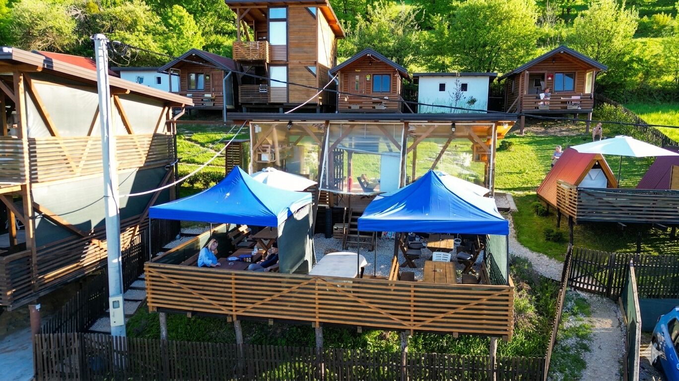 A wooden cabin complex with multiple levels, outdoor seating, and a glass-enclosed area.