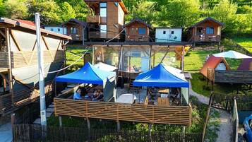 A wooden cabin complex with multiple levels, outdoor seating, and a glass-enclosed area.