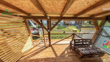 A wooden deck with a glass railing overlooking a garden.