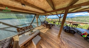 A wooden deck with a table and benches, overlooking a scenic landscape.