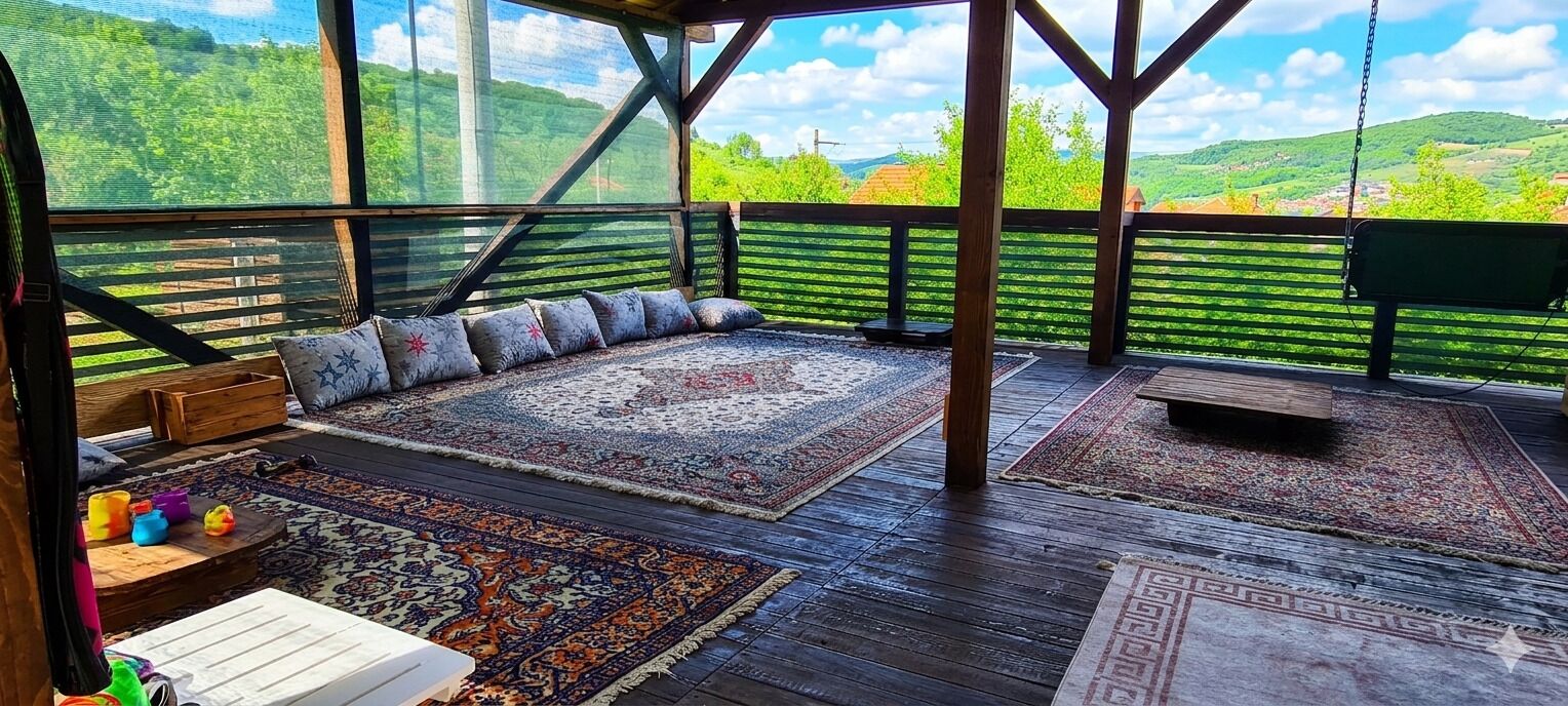 Un espacio de estar techado al aire libre con vistas a colinas verdes, suelo de madera y varios tapetes.