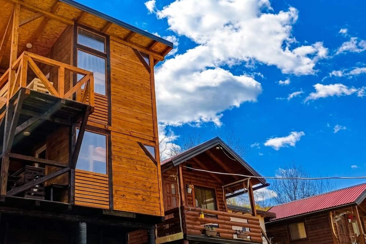 Eine Holzhütte mit Balkon, einem Fenster im zweiten Stock und einem roten Dach.