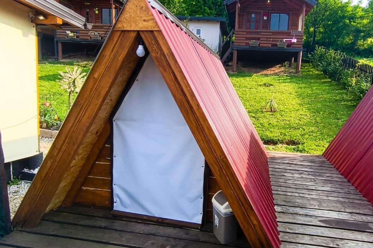 Eine Zelthütte mit weißem Innenraum, rotem Dach und einer Holzterrasse.