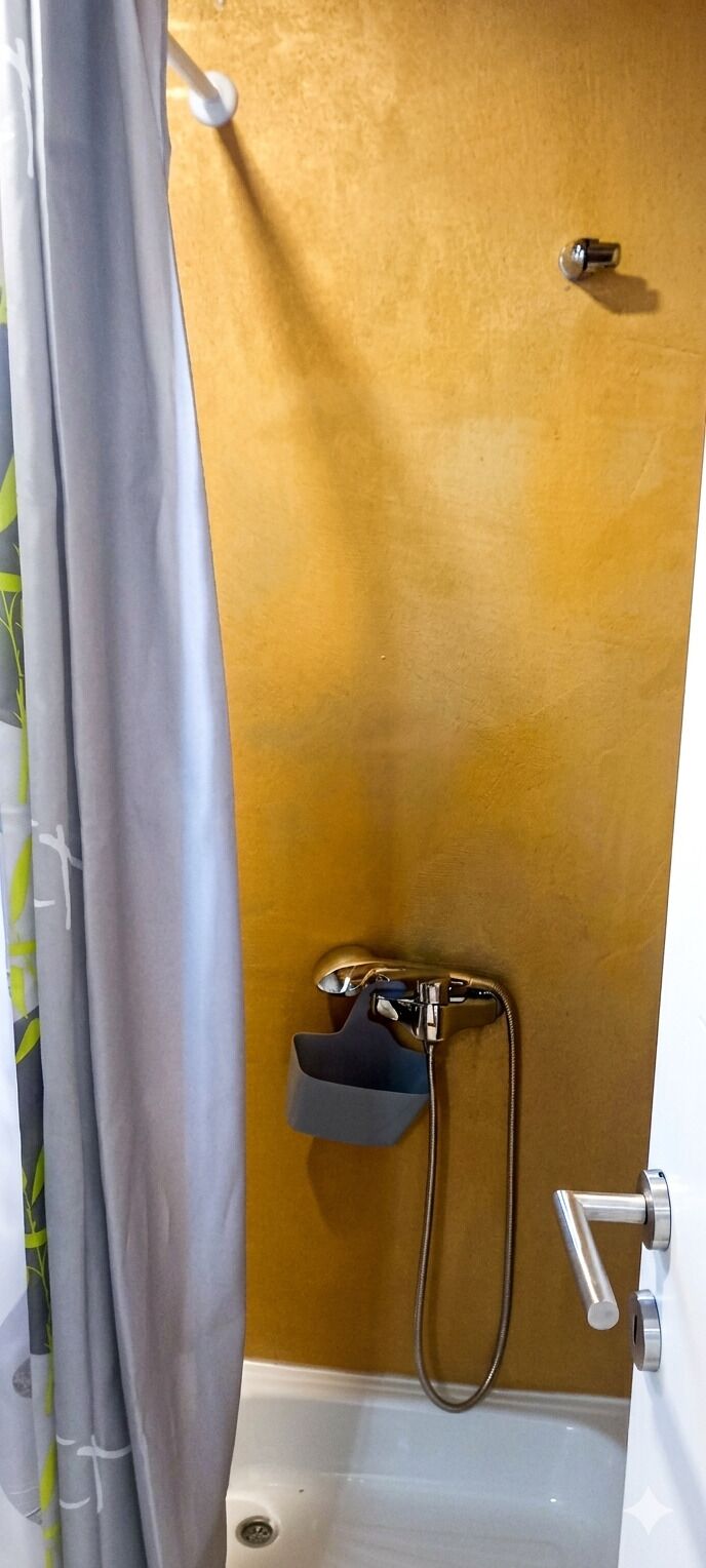 Un baño con ducha, toallero y picaporte.