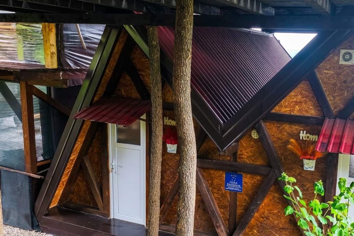 Ein traditionelles Holzhaus mit geneigtem Dach, einer Holztür und einem Schild mit dem Schriftzug 'Home'.