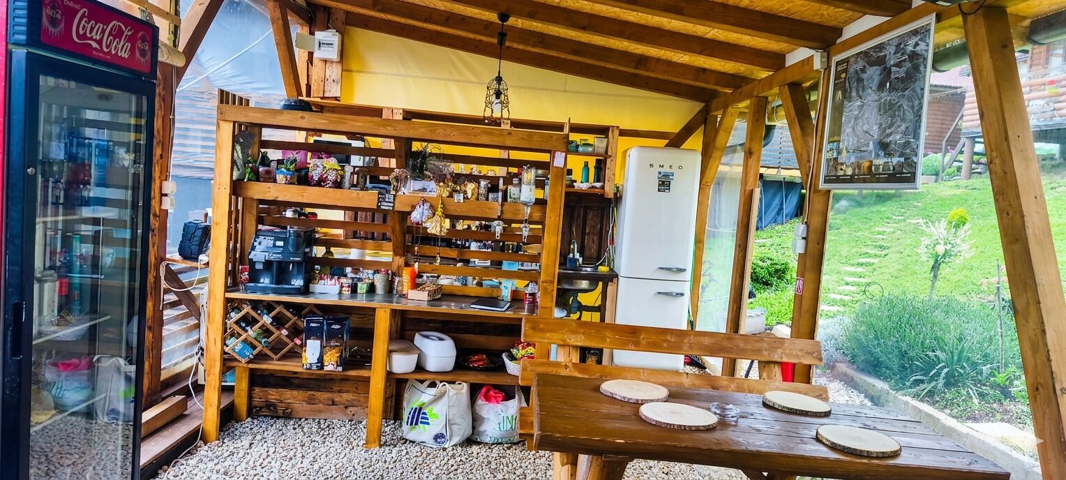 A rustic wooden structure with shelves stocked with various items, a refrigerator, and a Coca-Cola refrigerator.