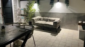 Un espace extérieur aménagé avec un canapé confortable, une table et des chaises, ainsi qu’une plante en pot.