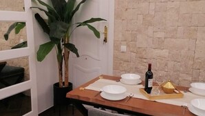 Un coin repas avec une table en bois dressée pour quatre personnes, une plante en pot et un mur en briques.
