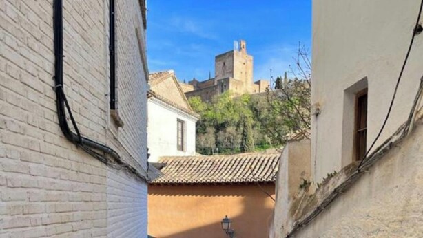 Une ruelle étroite, avec un chemin pavé menant à un bâtiment dont le toit est recouvert de tuiles.