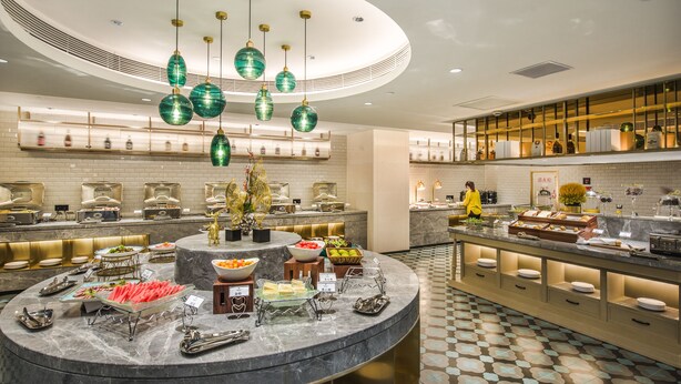 Uma área de buffet com diversos pontos de comida e um atendente.