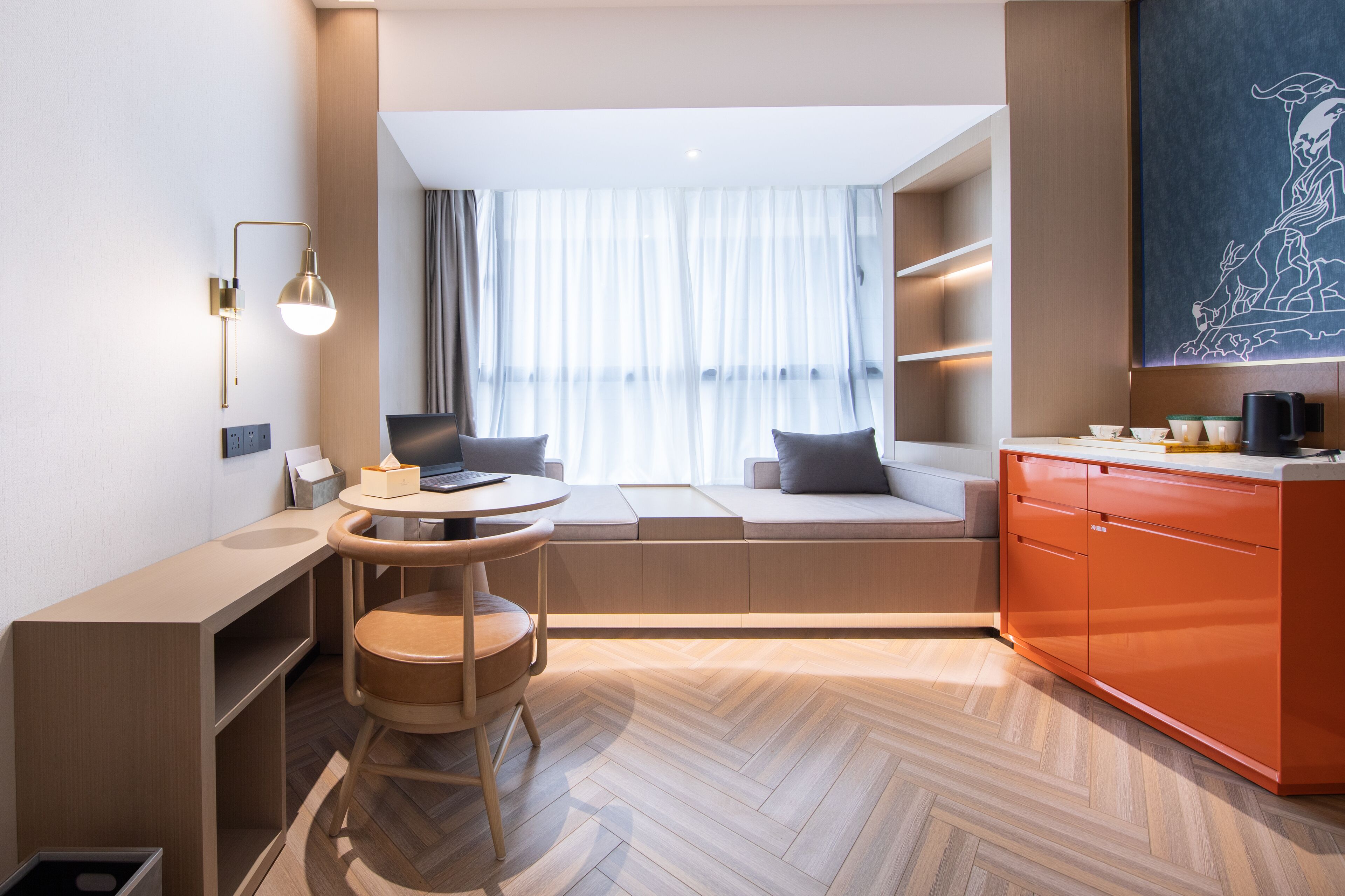 Una habitación de hotel moderna con comedor, sofá cama, mostrador de cocina y un amplio ventanal con cortinas traslúcidas.
