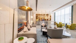 Um saguão de hotel moderno com área de estar, bar e vista para a cidade.