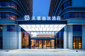 A hotel entrance with a modern design, featuring a glass facade and a covered entrance area. - GZ Baiyun Airport MeHood Liz Hotel T1 (Guangzhou)