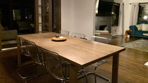 A dining area with a wooden table, clear chairs, and a woven light fixture. - HOT TUB | Decked Out Oasis | Nespresso Coffee Bar (South Bend)