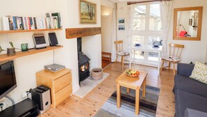 Een gezellige woonkamer met een open haard, houten meubels, een boekenkast en een eethoek met een tafel en stoelen.