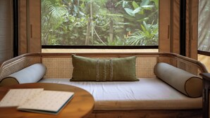 A room with a sofa facing a window with a jungle view. - Nadi Nature Resort - Adults Only (Penebel)