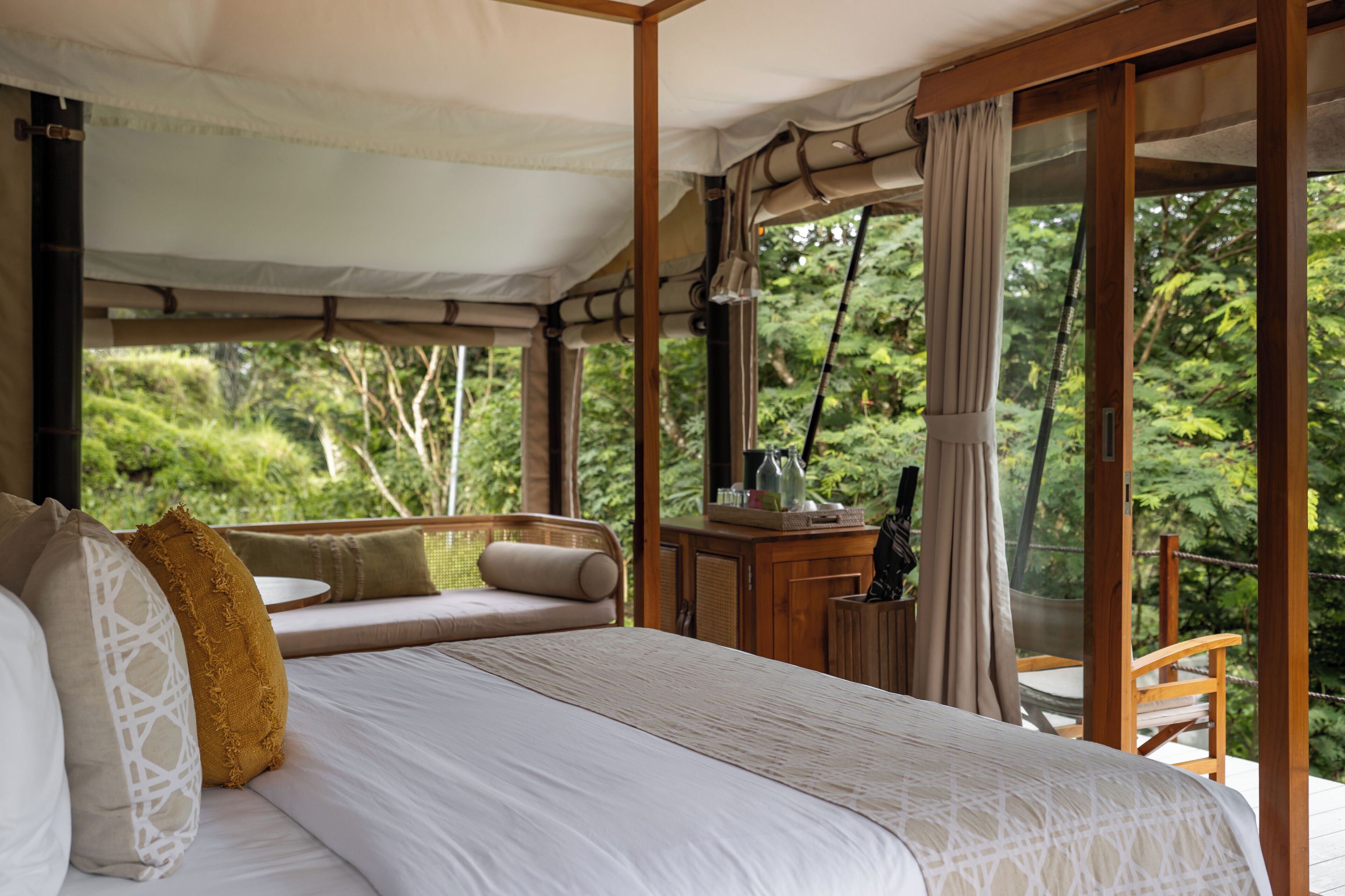 Un dormitorio con una cama grande, un escritorio de madera y vistas a abundante vegetación.