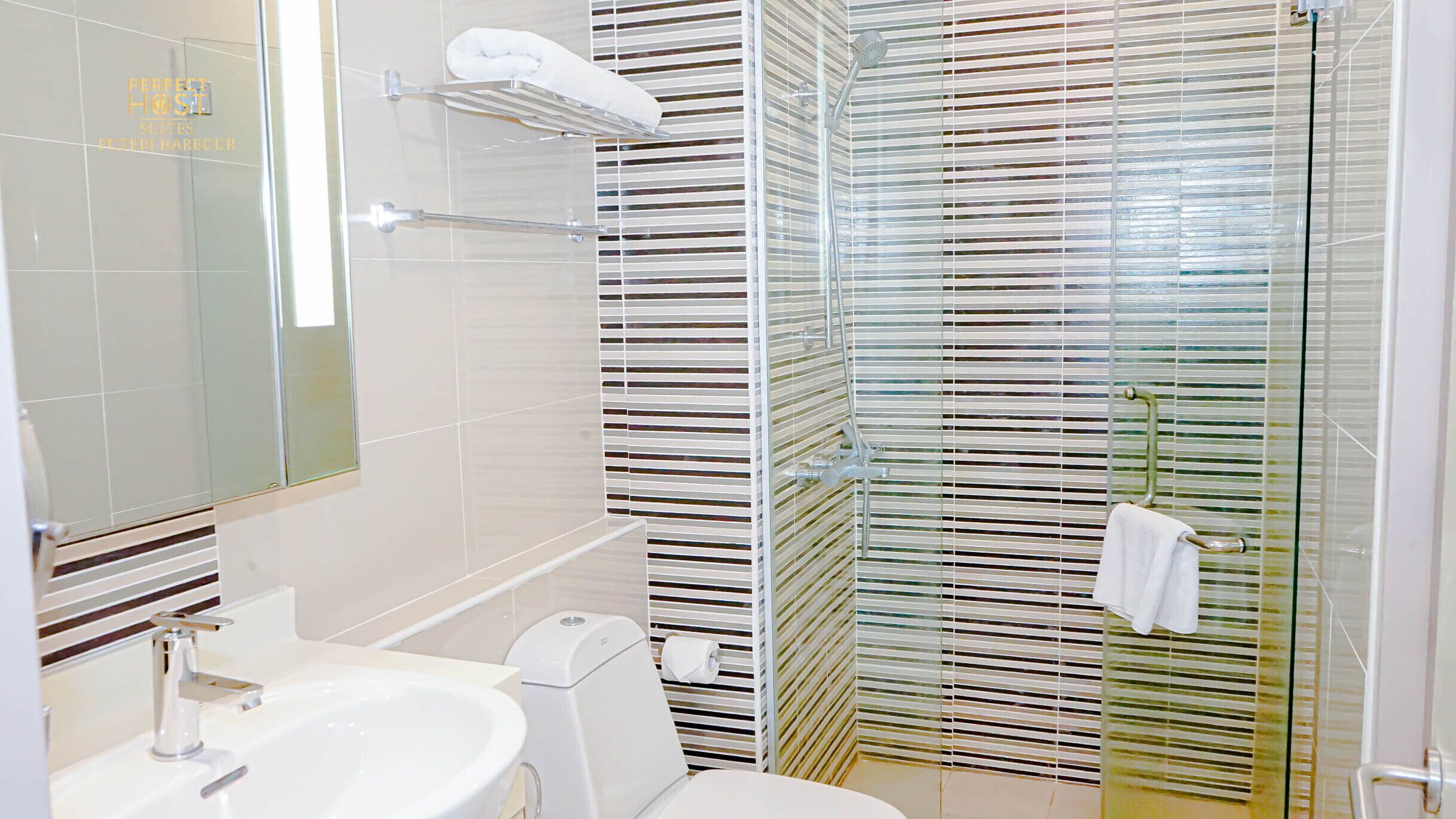 Et moderne badeværelse med glasbrusekabine, toilet og håndvask.