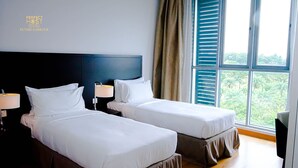 Une chambre d’hôtel avec deux lits, une tête de lit sombre, une fenêtre avec des stores et une vue sur la verdure.