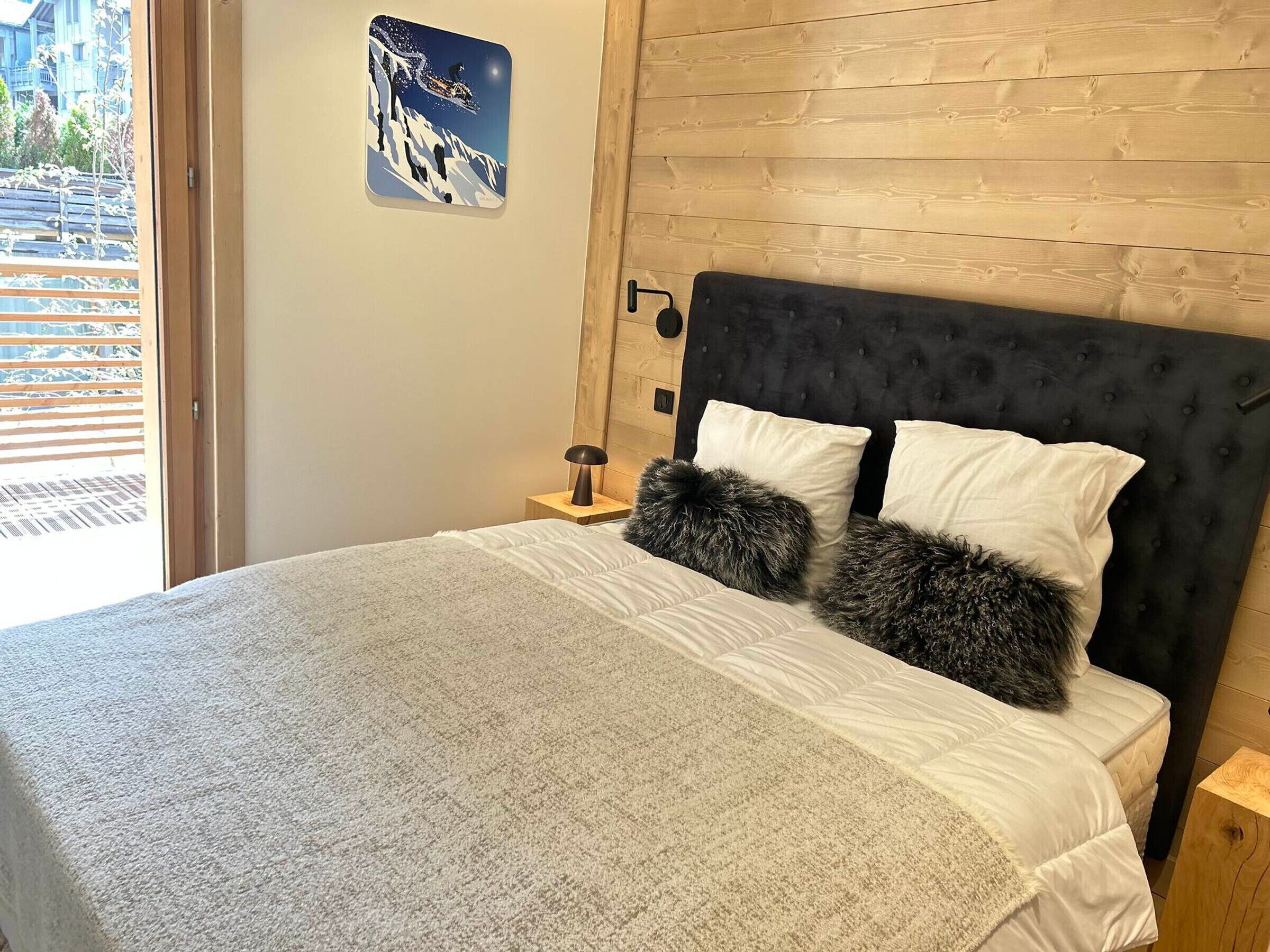 A bedroom with a large bed, a wooden headboard, and a nightstand with a lamp.