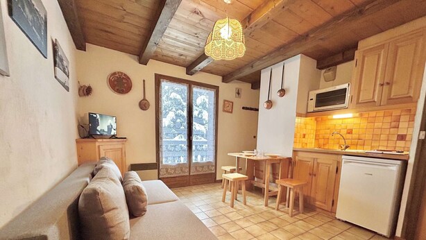 A cozy living room with a sofa and a dining area with a table and chairs. There is a kitchen with a microwave and a sink. - Cozy Studio Cabin for 4 in Crest-Voland, 100m from Ski Lifts and Village, Parking Included (Crest-Voland)