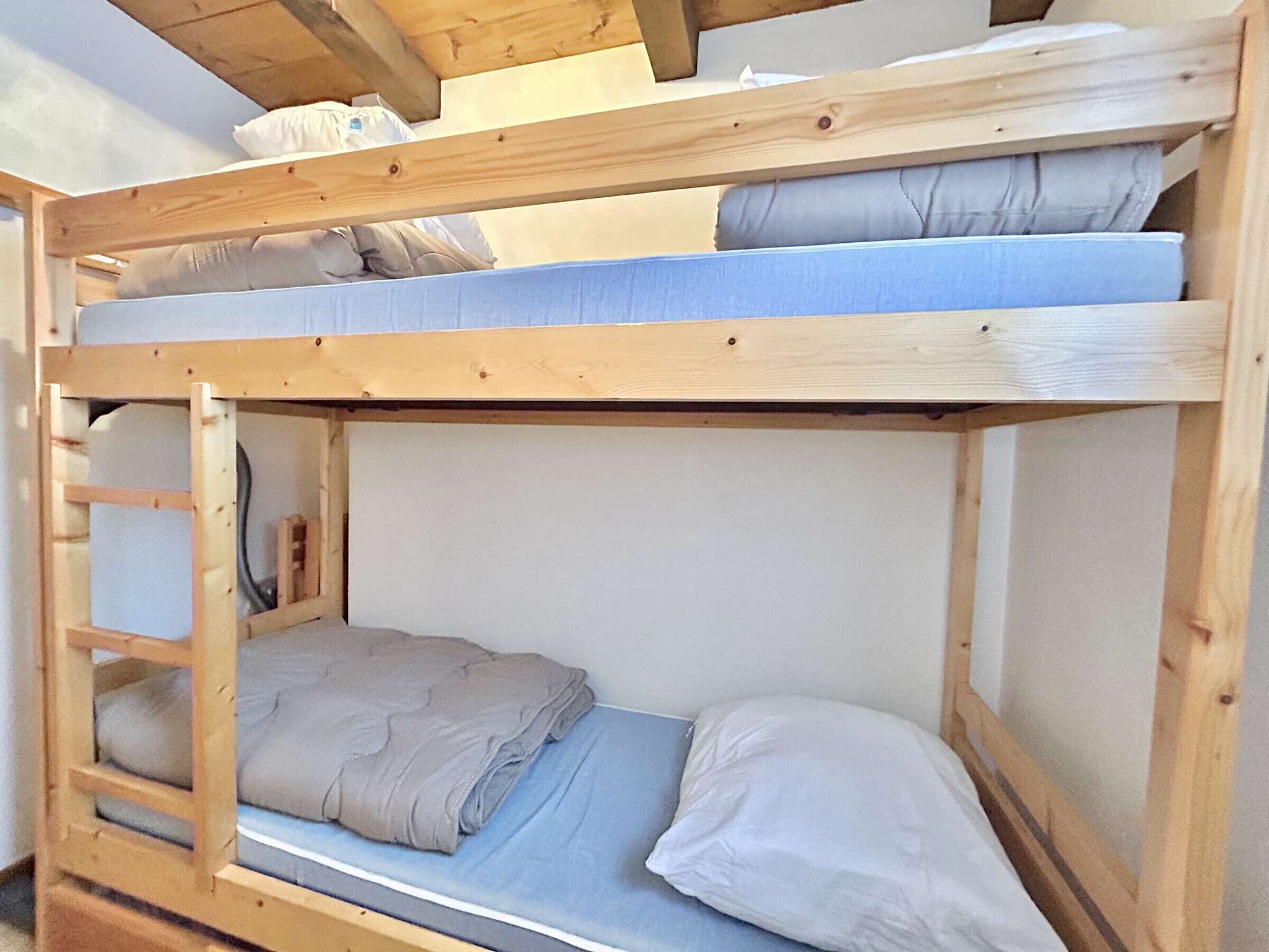 A bunk bed with two levels, each with a mattress and pillows.