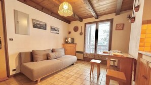 A cozy living room with a sofa, a wooden table, and a television. - Cozy Studio Cabin for 4 in Crest-Voland, 100m from Ski Lifts and Village, Parking Included (Crest-Voland)