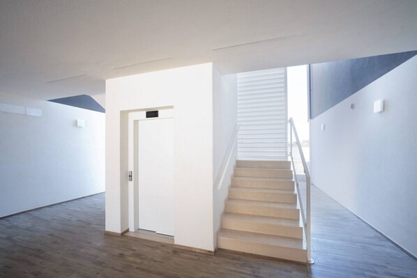 A modern interior with a staircase, a door, and a light-colored floor.