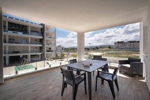 A modern apartment with a balcony, a dining area, and a view of the surrounding landscape.