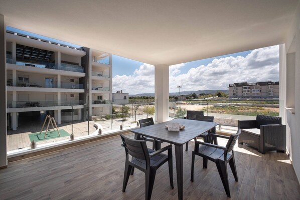 A modern apartment with a balcony, a dining area, and a view of the surrounding landscape. - WePuglia - LOI20 - Apt Levante (Monopoli)