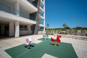 A modern building with multiple floors, outdoor play equipment, and a clear view of the sky.