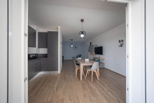 A modern kitchen with grey cabinets, a microwave, and a dining area with a table and chairs.