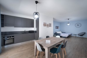 A modern kitchen with grey cabinets, a wooden dining table, and a nameplate.
