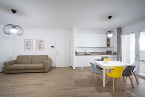 Eine moderne Wohnung mit Sofa, Esstisch, Stühlen, Küchenzeile und Bildern an der Wand.