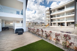 A modern building with multiple floors, outdoor seating area, and a children's play area.