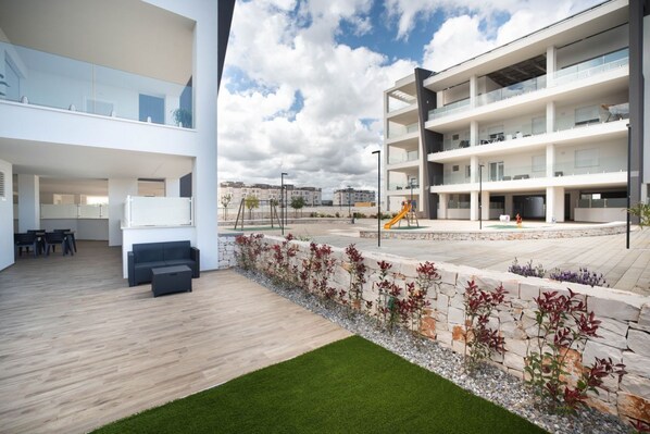 A modern building with multiple floors, outdoor seating area, and a children's play area.