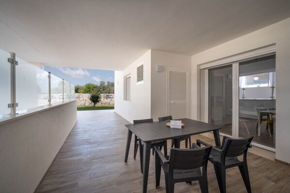 Eine moderne Wohnung mit Balkon, einem Essbereich mit Tisch und Stühlen sowie einer Glastür zum Küchenbereich.