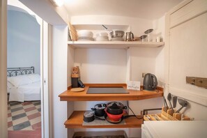 Une cuisine compacte avec un lit dans la pièce adjacente, une machine à café et un panneau indiquant qu’il s’agit d’un établissement WePuglia.