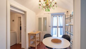 A compact kitchen with a dining area, a chandelier, and a small table with a woven placemat.