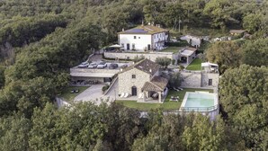 An aerial view of a property with a stone building, a pool, and a parking area surrounded by trees. - Villa Le Croci beautiful tuscan villas with infinity p/pool (Croci Di Calenzano)