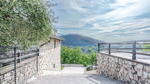 A stone pathway leading to a stone building with a metal fence on one side and a railing on the other, overlooking a mountainous landscape. - Villa Le Croci beautiful tuscan villas with infinity p/pool (Croci Di Calenzano)