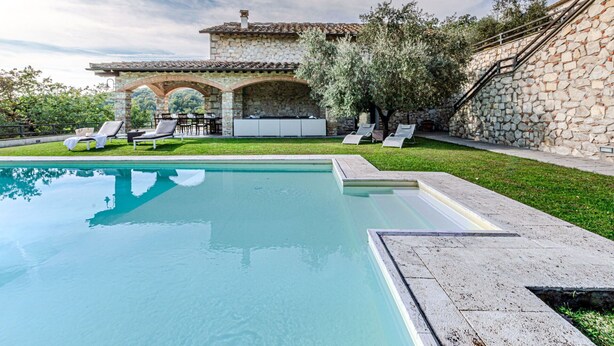 A swimming pool with lounge chairs and a stone building with arches. - Villa Le Croci beautiful tuscan villas with infinity p/pool (Croci Di Calenzano)