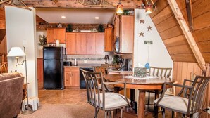 Eine gemütliche Küche mit Holzschränken, einem Esstisch mit Stühlen und einer Decke mit Holzbalken.